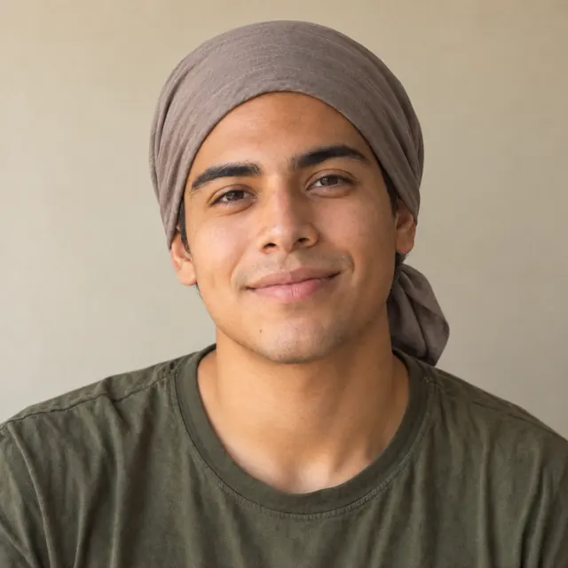A man in his twenties with chin-length wavy hair, wearing a soft headscarf