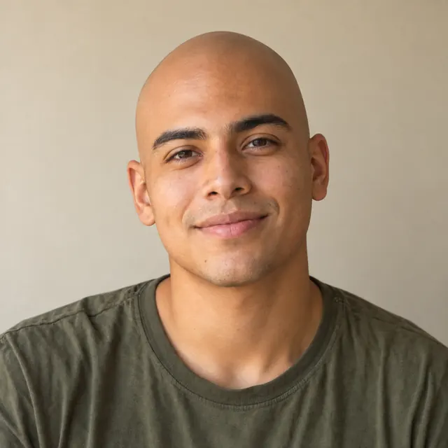 A man in his twenties with chin-length wavy hair, with a fully shaved head