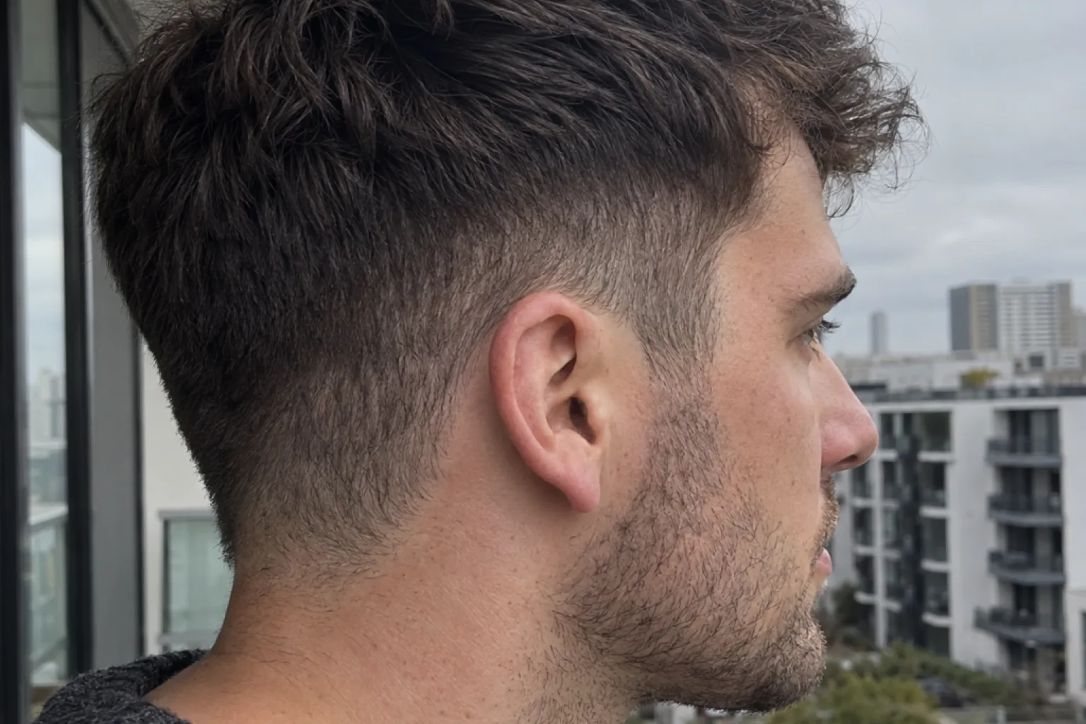 A bald fade three weeks after the cut, the shaved section grown into a soft stubble shadow with no crisp blend left