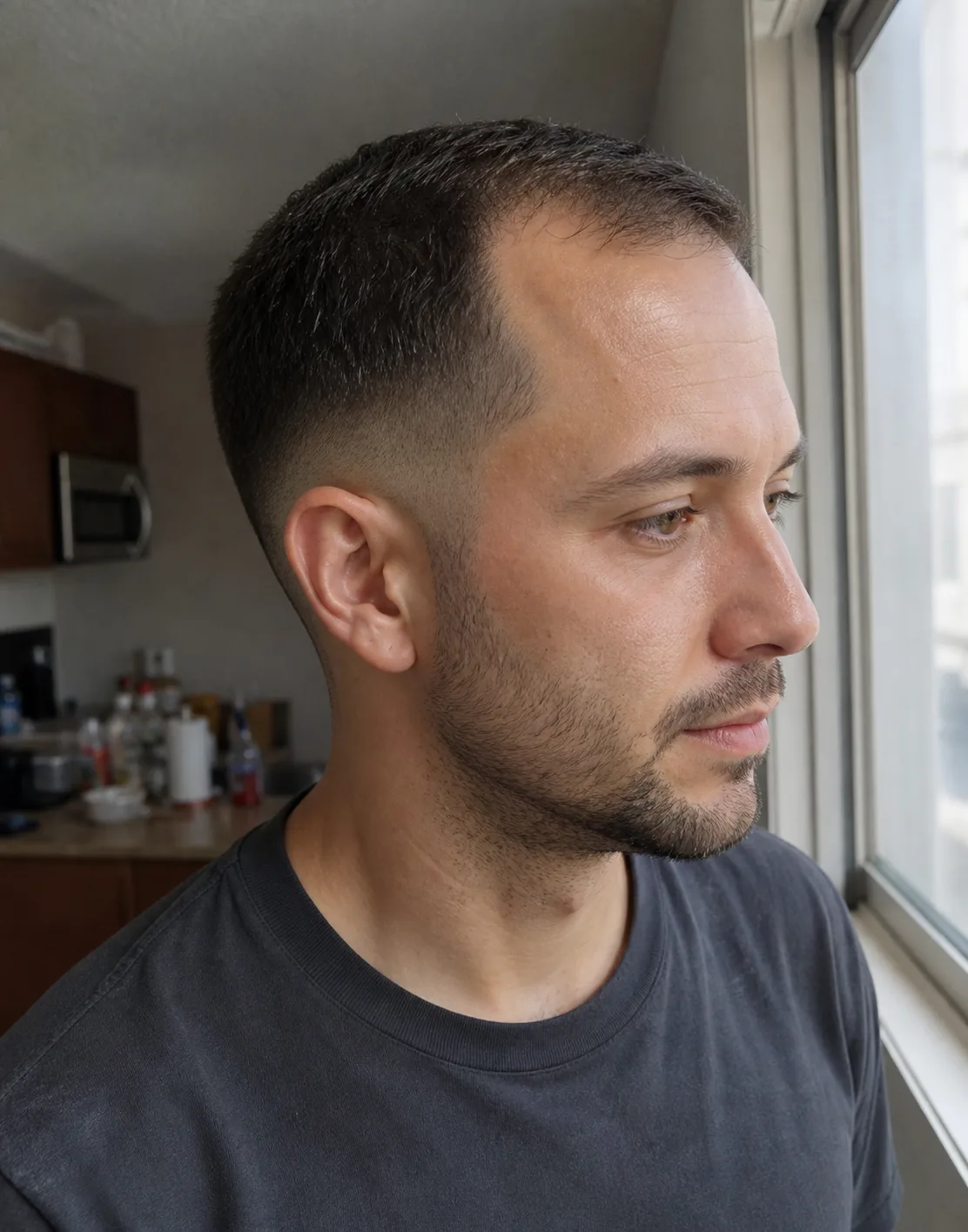 A man with fine hair and receding temples wearing a low fade and a short even crop on top.