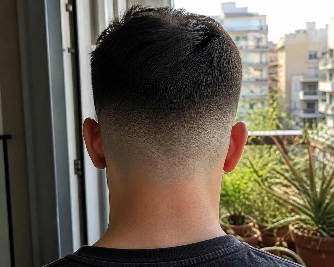 Close-up of the back of a neck showing the bottom of a fade blending into bare skin at a rounded, unsquared nape.