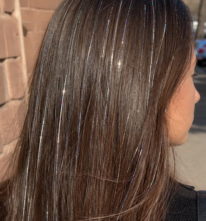 Crown of long brown hair with iridescent hair tinsel strands tied in at the part