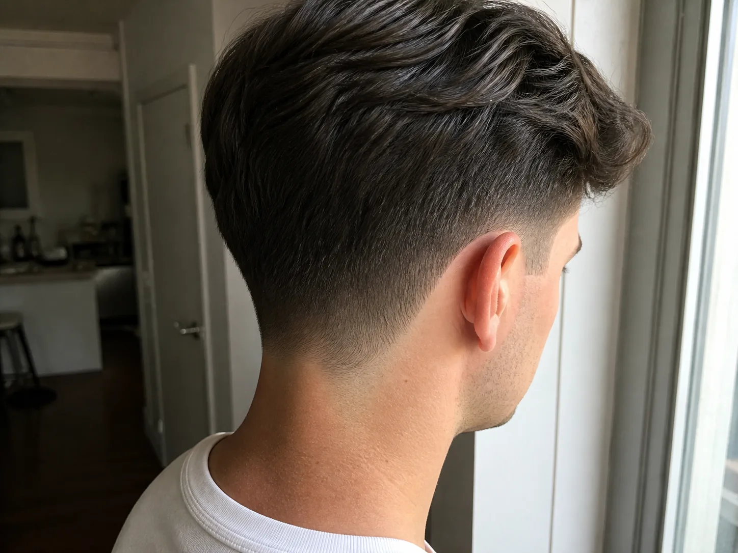 Rear view of a low taper fade showing the neckline at the nape faded softly out into the skin in a rounded shape rather than cut into a hard straight line