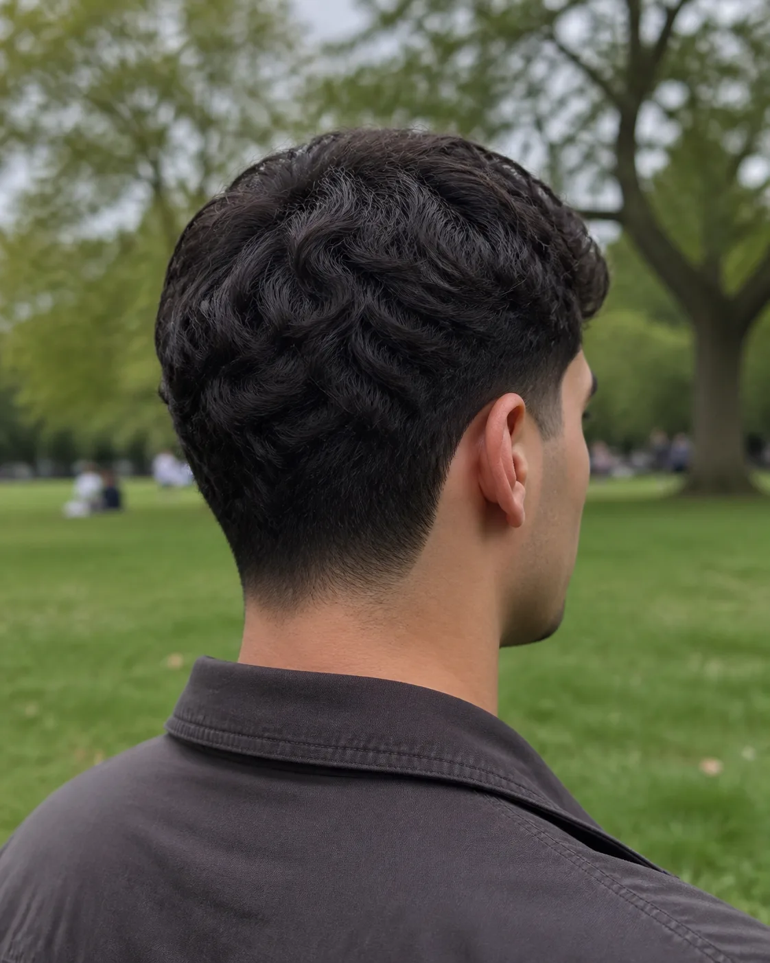 Three-quarter rear view of a mid taper fade, the gradient wrapping from the temple around behind the ear and down to a soft natural neckline at the nape
