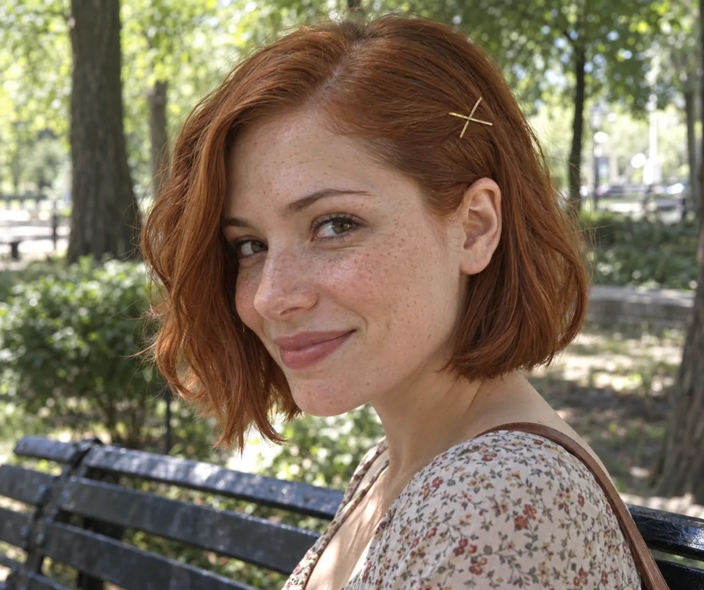 Woman on a park bench with a chin-length copper bob, one side pinned back with two crossed gold bobby pins