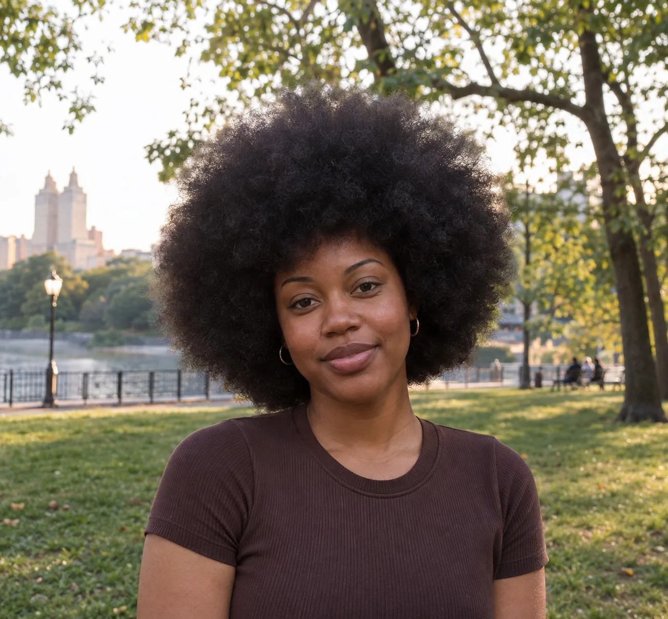 Woman with a large round black natural afro in a city park at golden hour