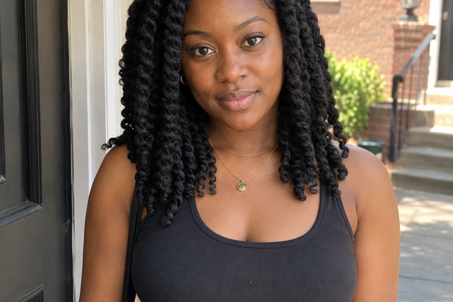 Woman with shoulder length black two strand kinky twists standing in a sunlit doorway