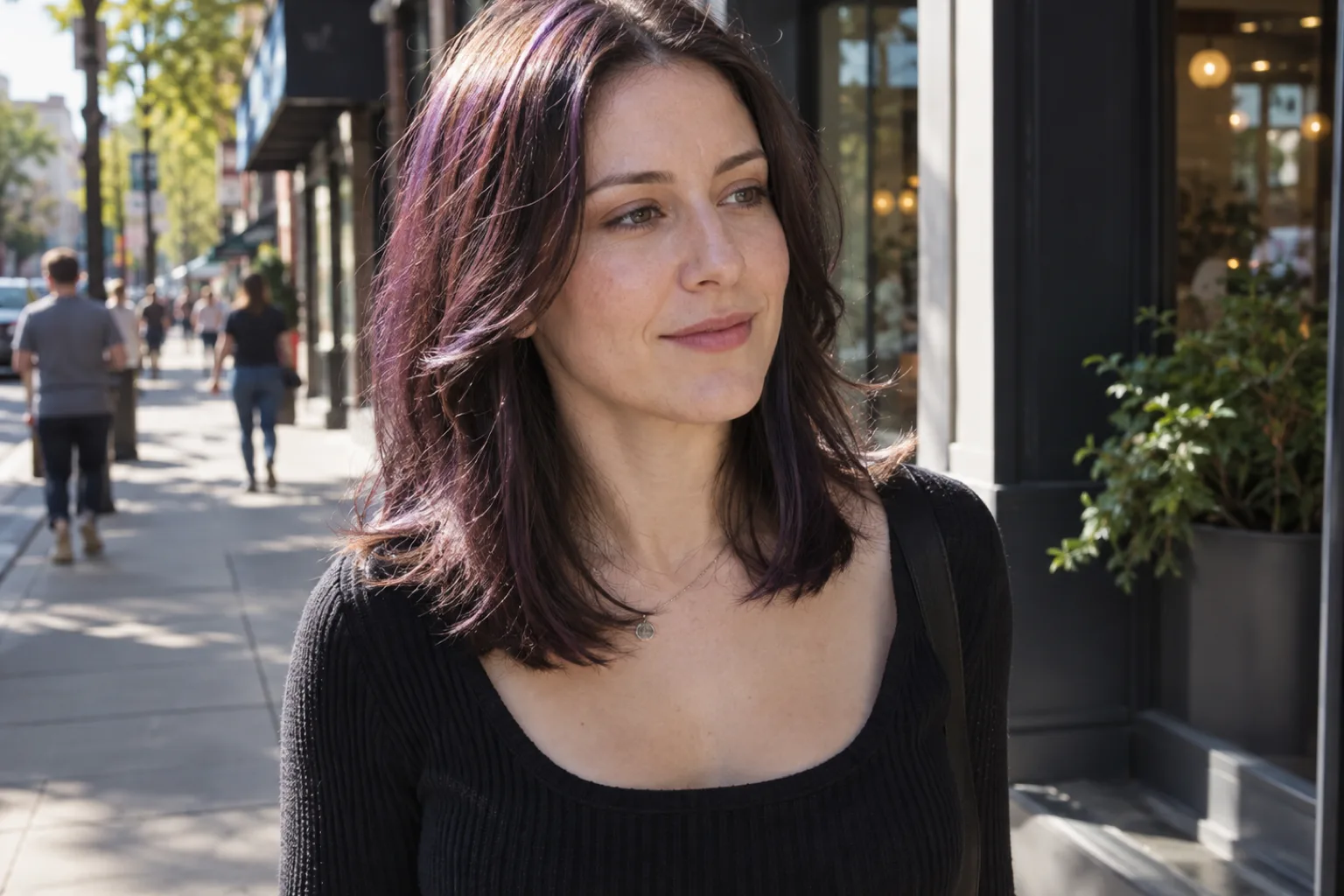 Woman with shoulder-length dark brown hair on a sunny sidewalk, violet tones showing through the sunlit strands